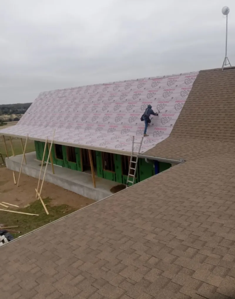 Worker preparing underlayment for a metal roof installation in Ecorse